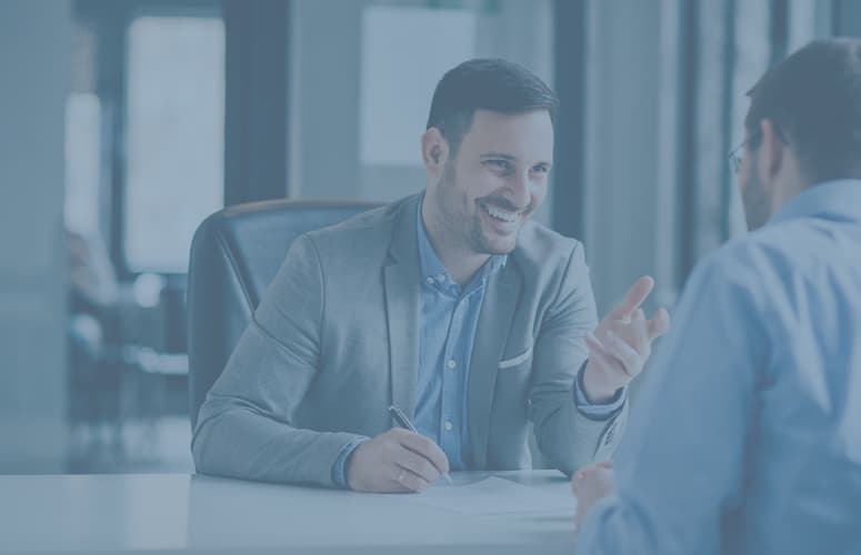 Two business men in suits are having a candid discussion in an office and taking notes.