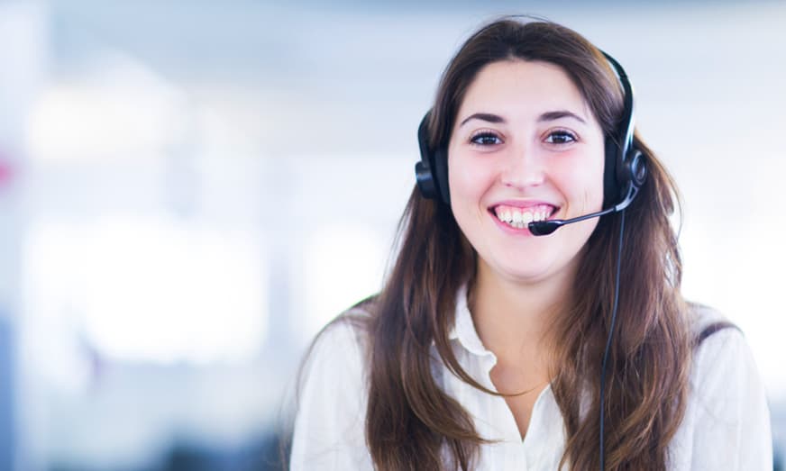 A headshot of a smiling business woman wearing a headset.