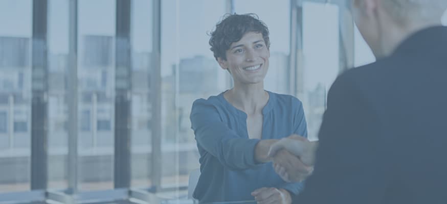 A woman is shaking hands with a man in a suit in an office.