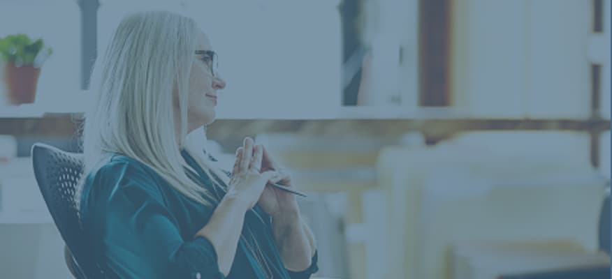 A business woman is sitting down and listening patiently to someone not pictured.