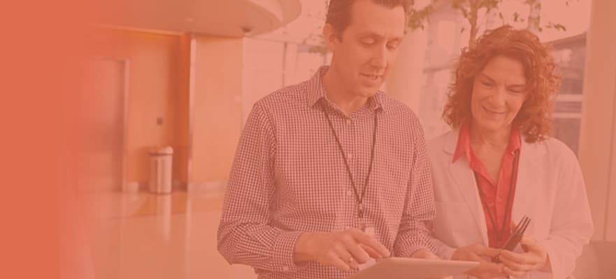 A business man is explaining something on a mobile device to a female doctor.