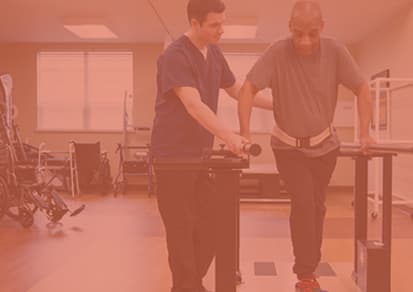 A physical therapist is helping an older man do running exercises on a rehabilitation machine.
