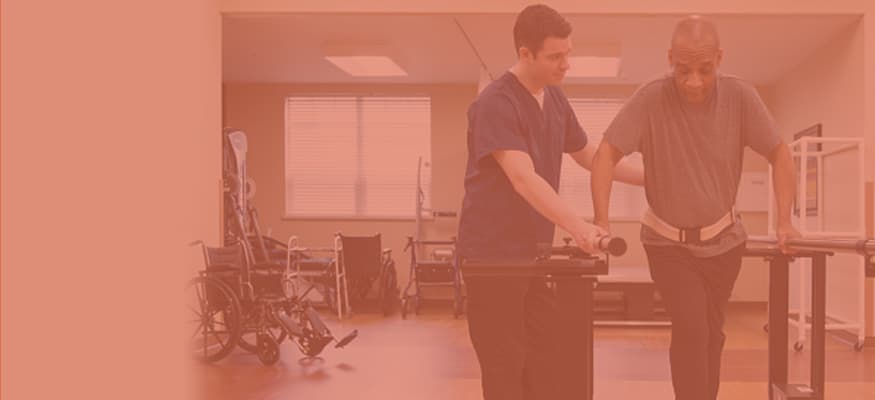 A physical therapist is helping an older man do running exercises on a rehabilitation machine.