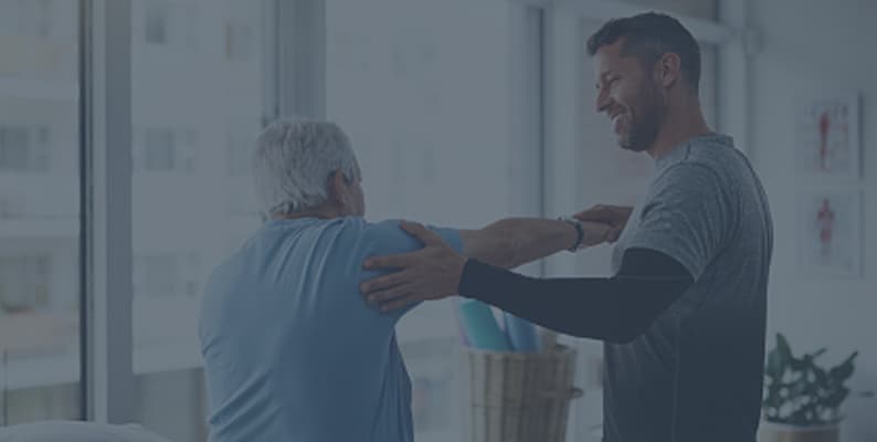 A physical therapist is doing arm stretches with an older man.