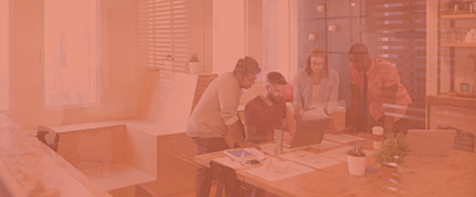 A group of business colleagues are having a discussion of some reports at an office desk.