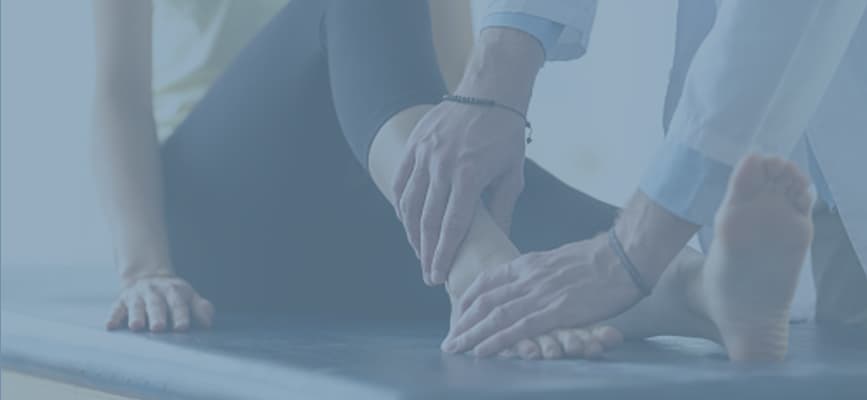 An orthopedic doctor is investigating the foot of a female patient.