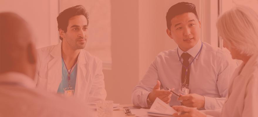 A group of doctors are having a discussion over documents while sitting at a table.