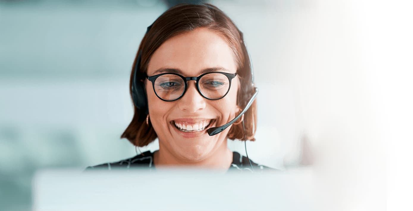 A close-up of a woman’s face, smiling and speaking into a headset.