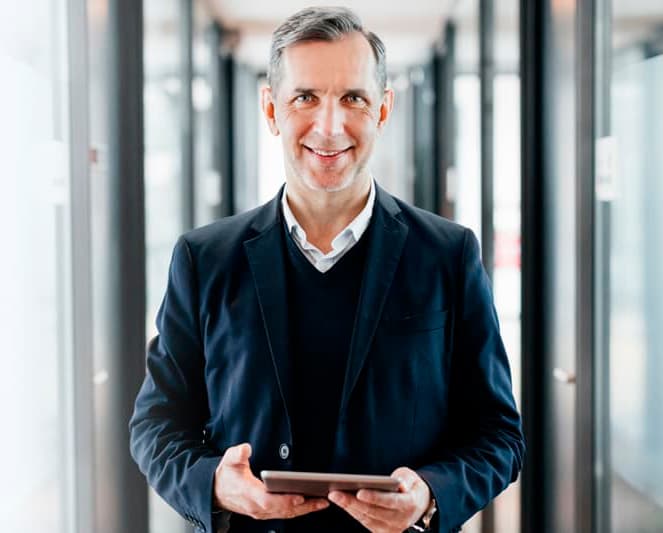 A front-facing shot of a man in an office holding an iPad.